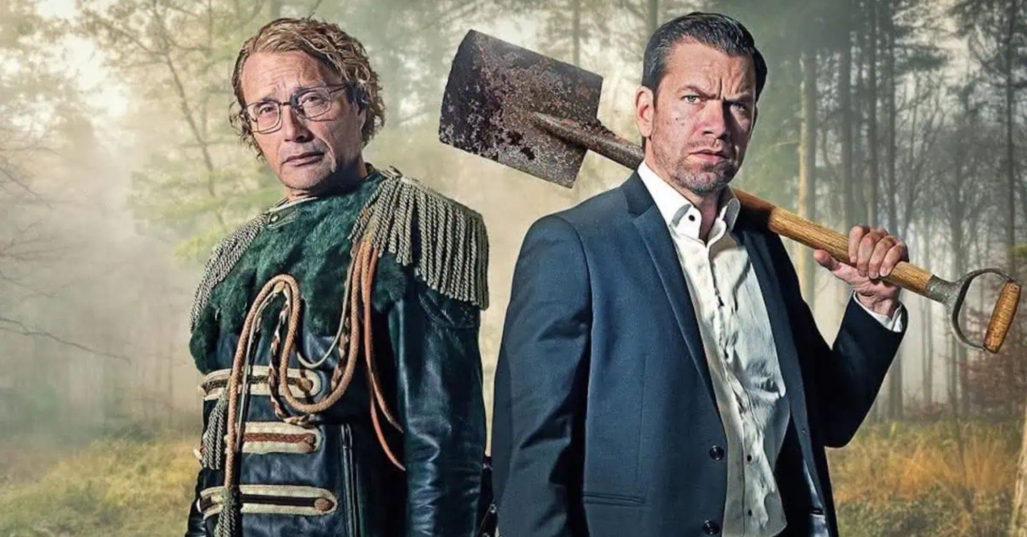 Manfred in his blue tassled Sergeant Pepper outfit, stands back-to-back with his shovel-wielding brother Anker in a pit in the woods.